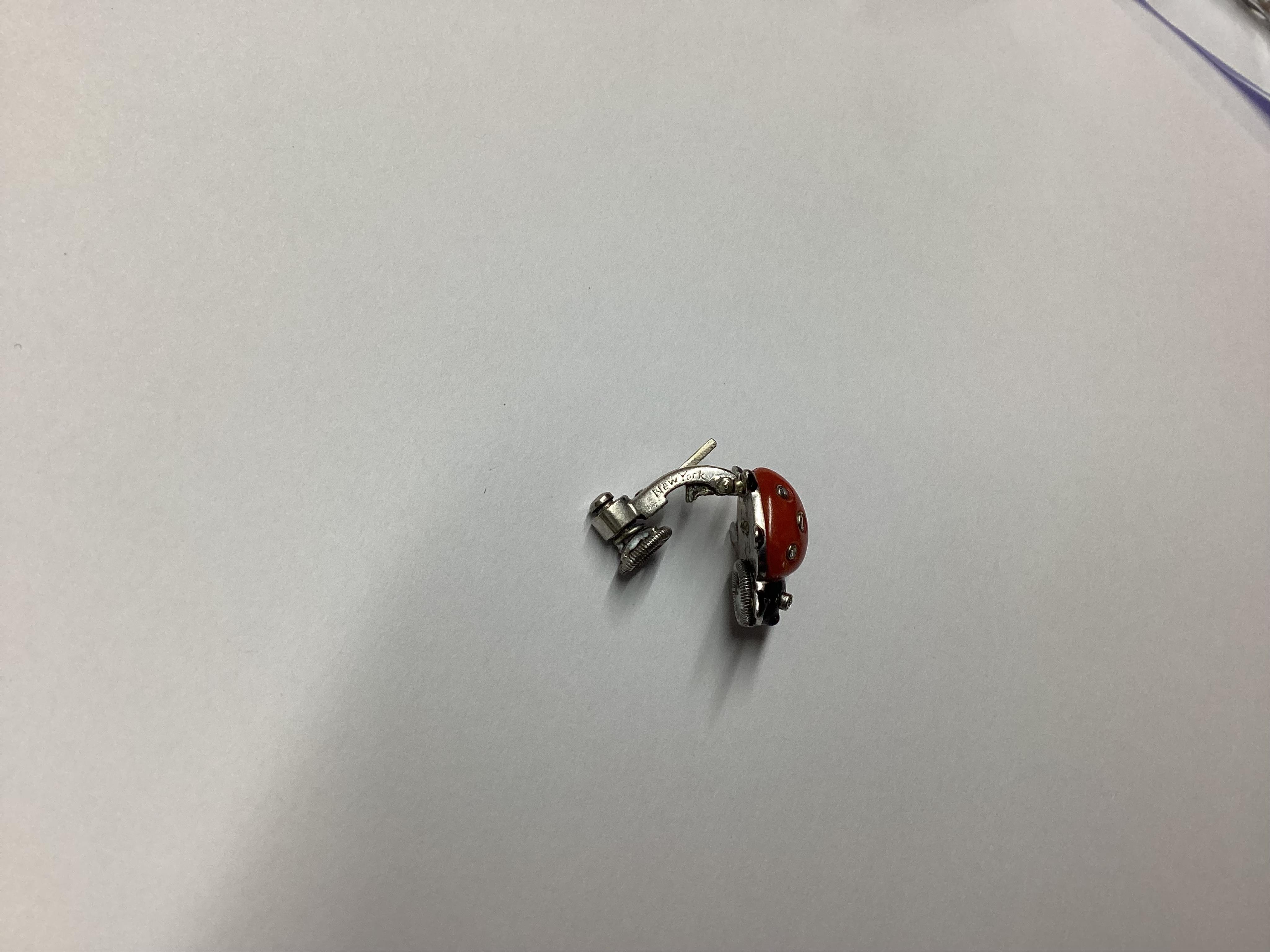 A pair of white metal, enamel, coral and diamond ladybird ear clips, bearing Cartier, New York signature and inscribed 18k